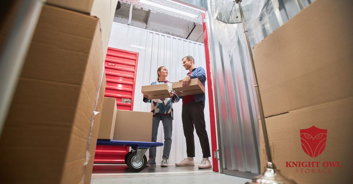 A man and woman holding packing boxes inside a clean, secure indoor storage unit.